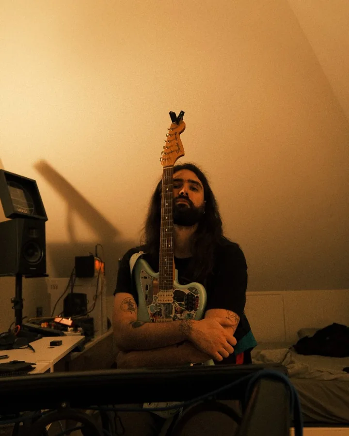 soram - portrait with electric guitar in a warm home studio